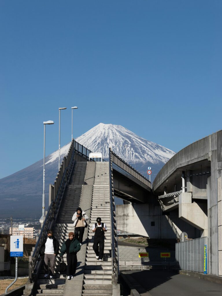 Capture of pedestrians on a bridge with Mount Fuji in the background, showcasing urban and natural contrast.